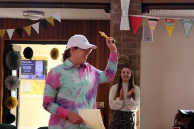 Daniel wears a cap and a homemade tie dye shirt as he smiles with award