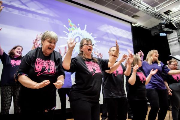 Members of Hands & Voices sing together in front of a purple background