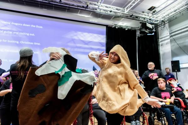 A woman dressed as a Christmas turkey dances with crowd of people behind her