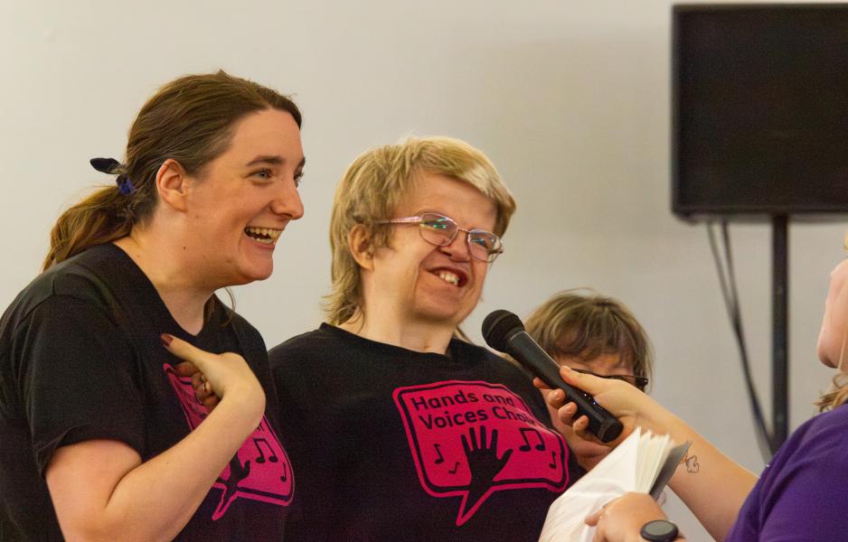 Hands & Voices members smiling and singing into a microphone