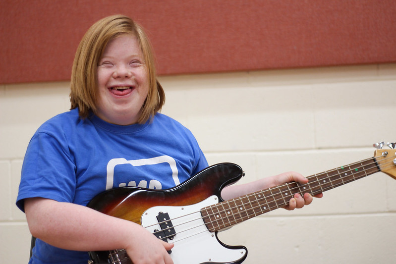 A young musician smiling while playing an electric guitar at an AAM session