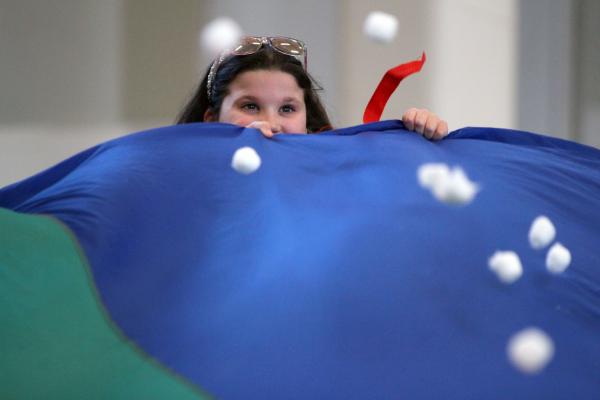 A participant holds a parachute while cotton balls move about representing snow