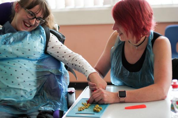 Picture of a participant and support worker chopping up ingredients