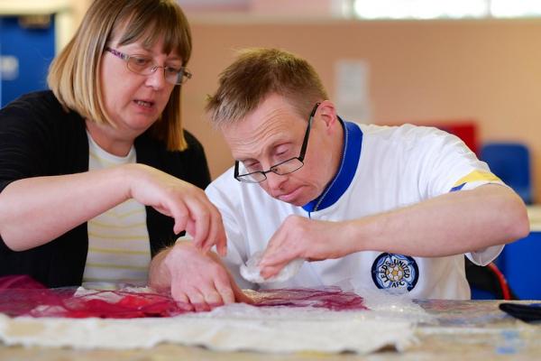 Participant and support worker creating a collage