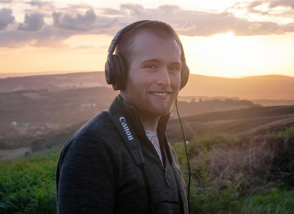 Peter Baumann stands against a sunset background