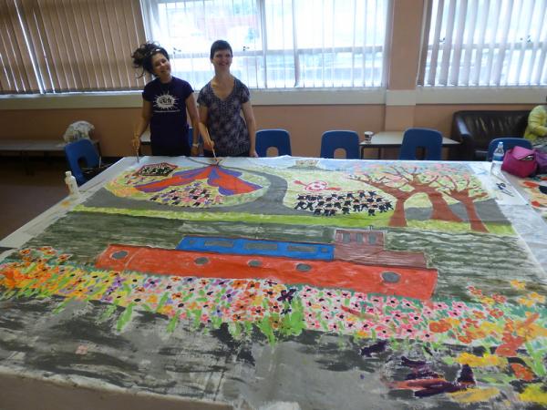 Participant and AAM session artist with a huge mural painted by everyone