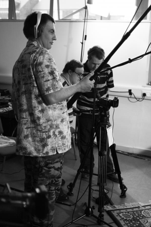 AbleWeb participant behind the camera, holding a boom mic and wearing headphones