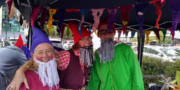 Three people dressed as gnomes pose in colourful pointy hats and wool beards