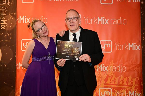 Ian Donaghy poses with his award in front of a bright orange background